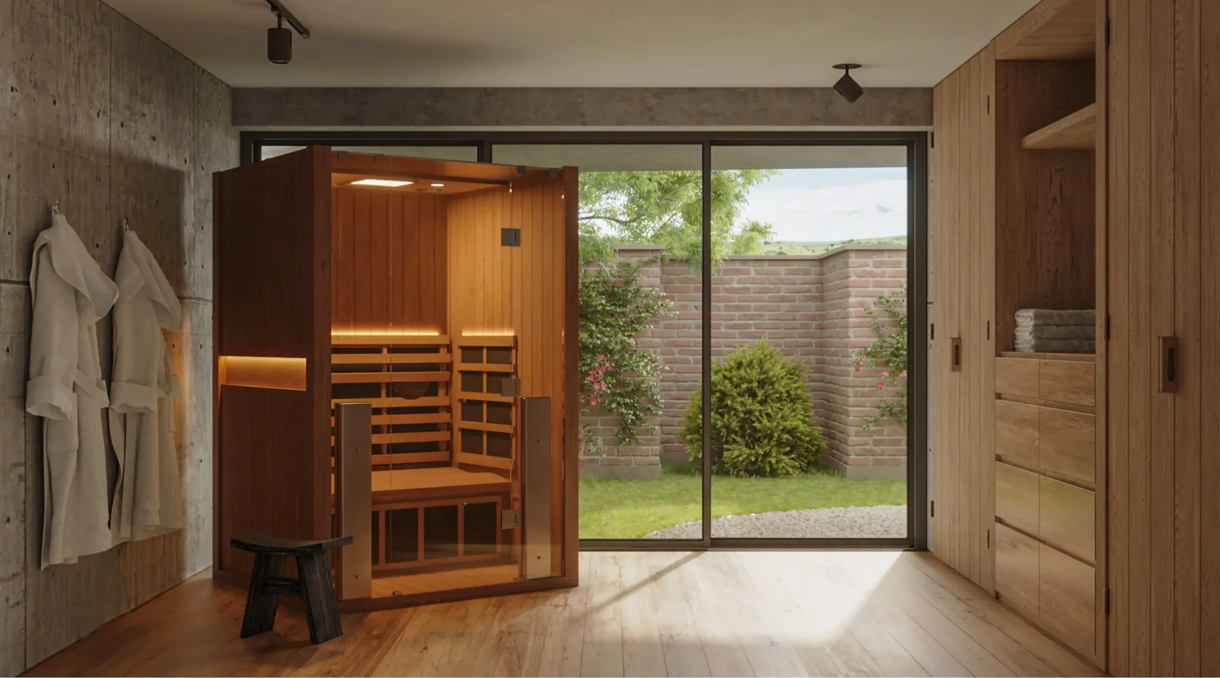 Clearlight's rendering of an infrared cabin in a room with concrete walls, robes on hooks, and a glass wall opening onto a walled garden.
