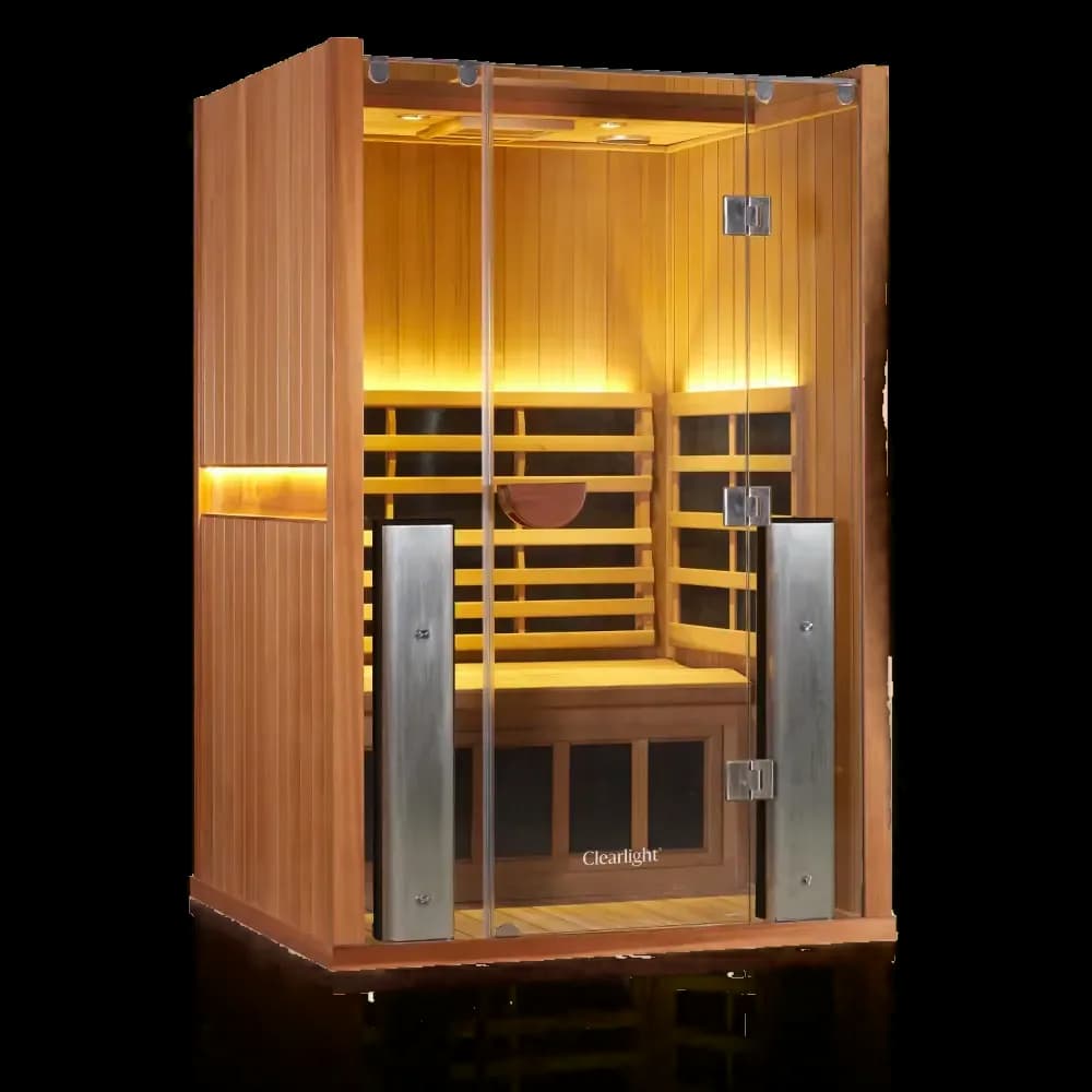 Clearlight Sanctuary sauna in reddish wood, glass front with tall metal cased heaters framing the door and warm interior light