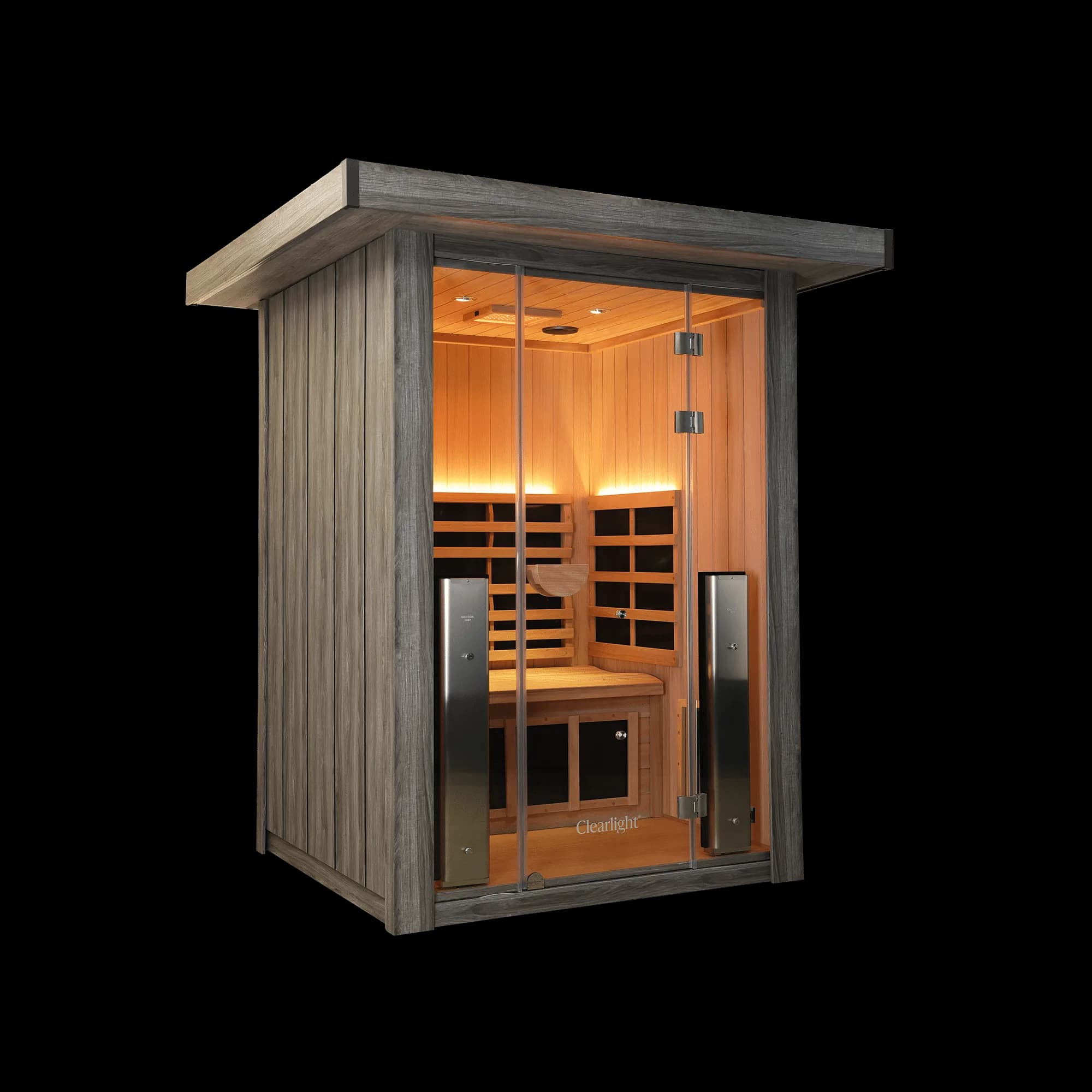 Clearlight Sanctuary Outdoor 2 infrared sauna from the front left corner, grey driftwood finish exterior and roof cap, glass front showing the lit interior and two heater towers