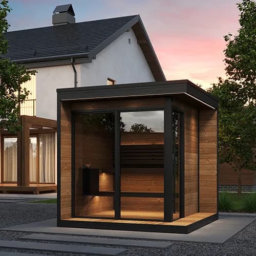 SaunaLife's rendering of the GL6 Outdoor Cabin, a glass-fronted sauna lit from inside on a gravel yard beside a house at dusk. A sauna from the same maker, not the R3 outdoor shower.