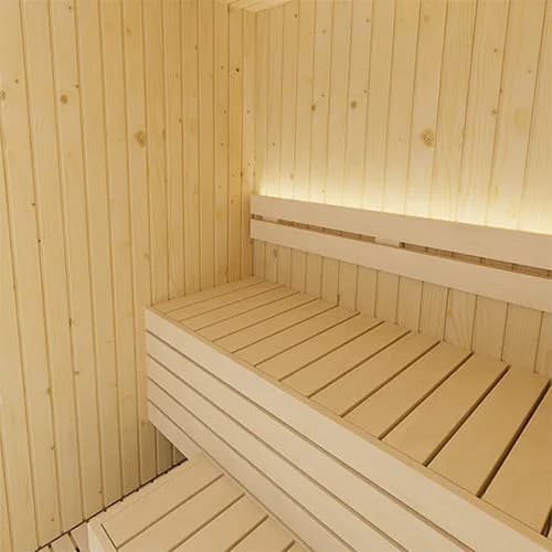 SaunaLife's image of the inside of the X2 indoor sauna: light spruce walls and a two-level bench, a soft light strip under the backrest.